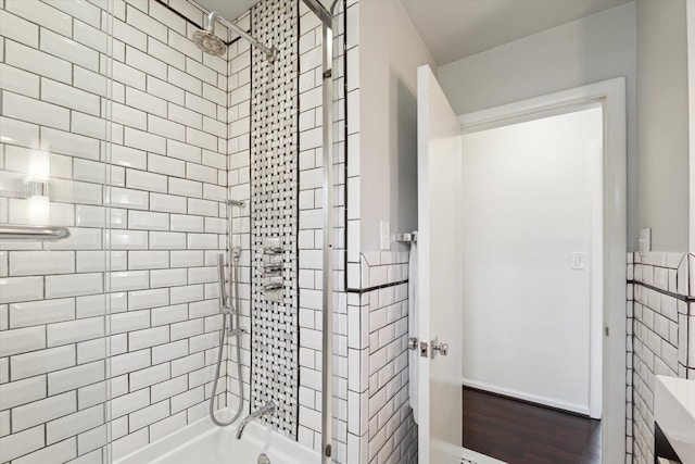 bathroom featuring wainscoting, tile walls, and tiled shower / bath combo