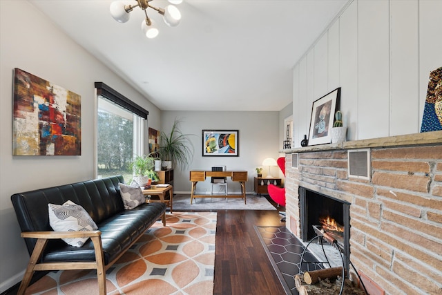 living area featuring visible vents, dark wood-type flooring, baseboards, a warm lit fireplace, and a notable chandelier