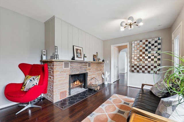 living area with a notable chandelier, a warm lit fireplace, baseboards, and wood finished floors