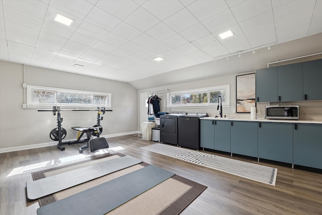 exercise area with independent washer and dryer, a sink, wood finished floors, baseboards, and vaulted ceiling