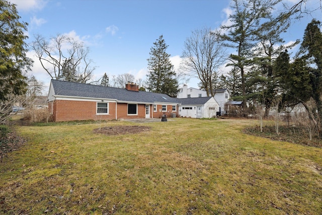 back of house featuring a yard, brick siding, and a chimney