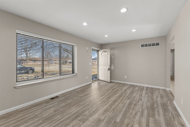 empty room featuring wood finished floors, visible vents, and baseboards