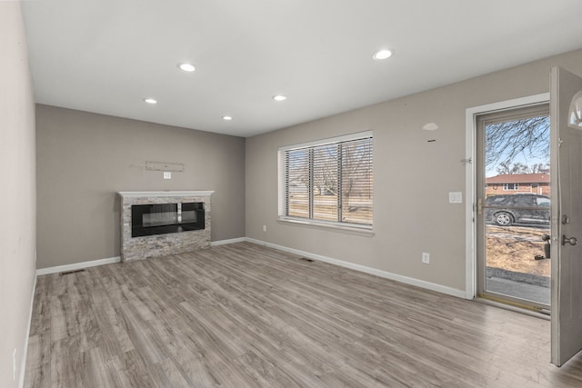 unfurnished living room with recessed lighting, visible vents, wood finished floors, and a glass covered fireplace