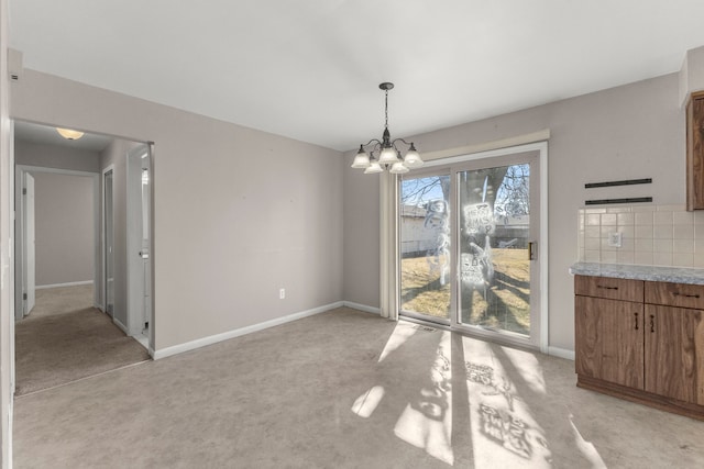 unfurnished dining area featuring light colored carpet, baseboards, and a chandelier