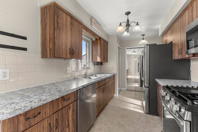 kitchen featuring tasteful backsplash, brown cabinets, a notable chandelier, stainless steel appliances, and a sink