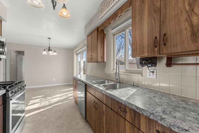 kitchen featuring tasteful backsplash, baseboards, appliances with stainless steel finishes, brown cabinetry, and a sink