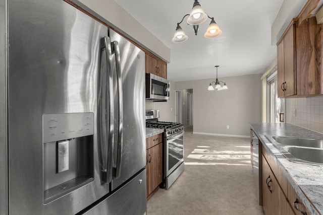 kitchen with decorative light fixtures, backsplash, appliances with stainless steel finishes, an inviting chandelier, and brown cabinetry