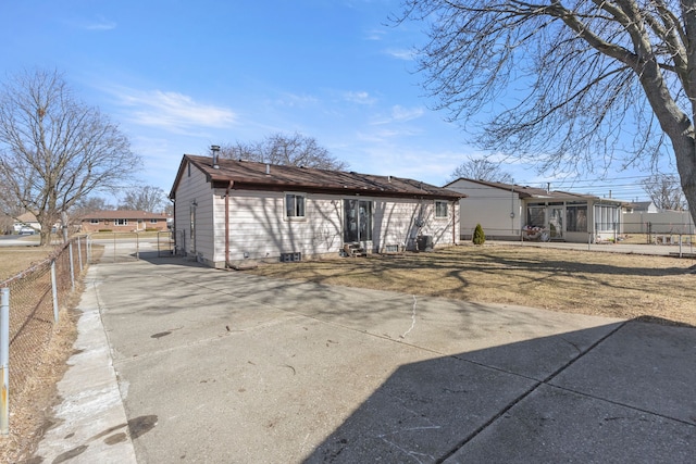 back of property with concrete driveway, a yard, and fence