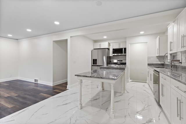 kitchen featuring a sink, backsplash, appliances with stainless steel finishes, and dark stone countertops