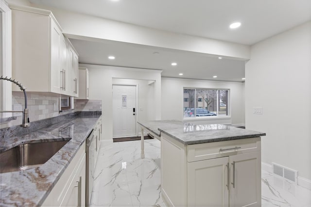 kitchen with visible vents, decorative backsplash, recessed lighting, marble finish floor, and a sink