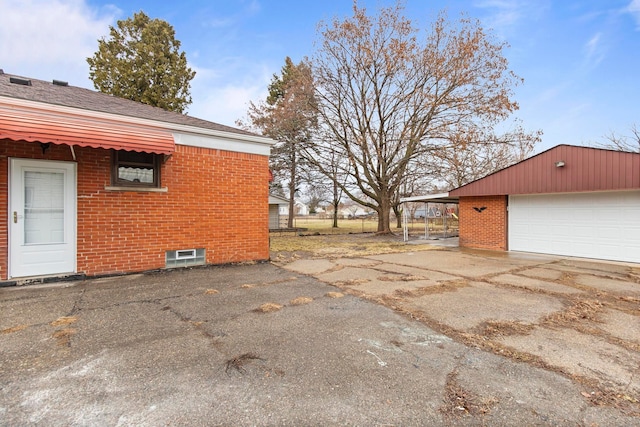 view of side of home with a garage, brick siding, and roof with shingles