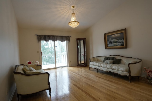 sitting room with vaulted ceiling, an inviting chandelier, and wood finished floors