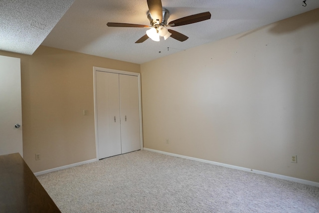 unfurnished bedroom featuring a textured ceiling, a closet, carpet flooring, and baseboards