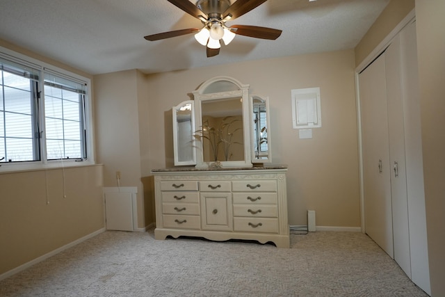 unfurnished bedroom featuring light carpet, ceiling fan, a closet, and baseboards