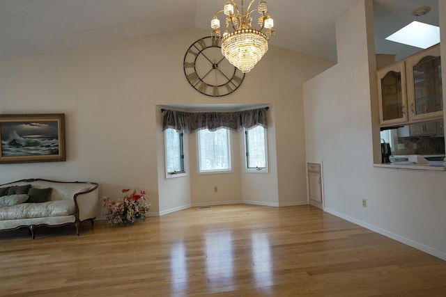 interior space featuring light wood-style flooring, baseboards, vaulted ceiling, and a notable chandelier