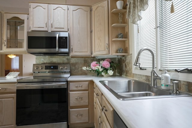 kitchen featuring light brown cabinets, stainless steel appliances, a sink, light countertops, and tasteful backsplash