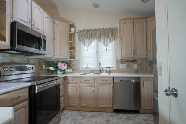 kitchen featuring light countertops, stainless steel appliances, a sink, and light brown cabinetry