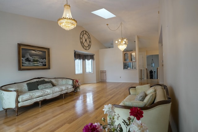 living room with high vaulted ceiling, a skylight, wood finished floors, baseboards, and an inviting chandelier