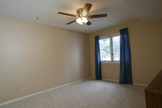 carpeted empty room featuring ceiling fan, a textured ceiling, and baseboards