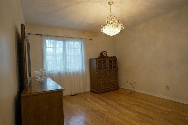 interior space featuring light wood finished floors, visible vents, baseboards, and a notable chandelier