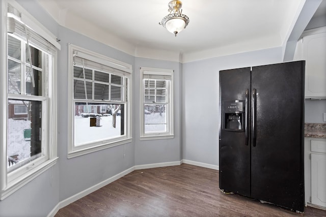 kitchen with baseboards, dark wood finished floors, black fridge, and white cabinets