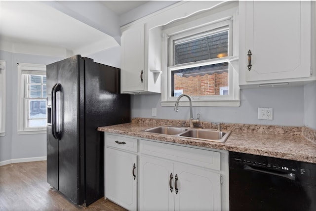 kitchen featuring white cabinets, black appliances, baseboards, and a sink