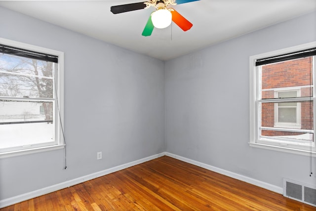 spare room with visible vents, ceiling fan, baseboards, and wood finished floors