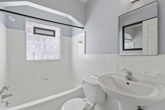 bathroom featuring a sink, tile walls, toilet, and shower / bath combination