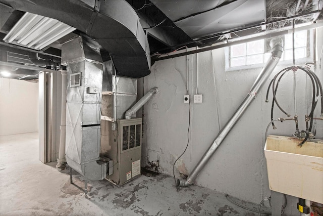 below grade area featuring heating unit, visible vents, and a sink