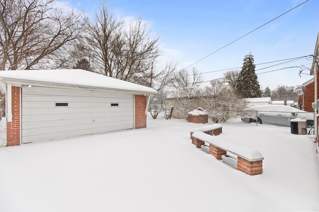 snowy yard featuring an outbuilding, a garage, and fence