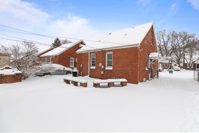 snow covered rear of property with brick siding