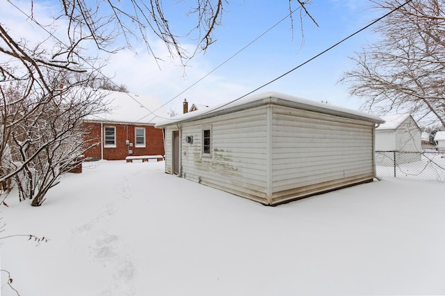 snow covered back of property with fence