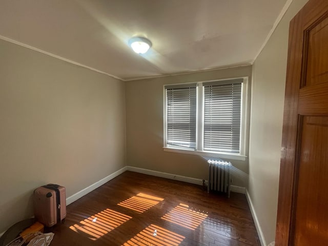 unfurnished room with baseboards, crown molding, wood finished floors, and radiator