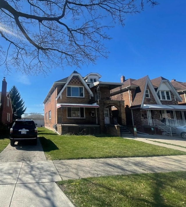 view of front of house featuring driveway, a front yard, and brick siding