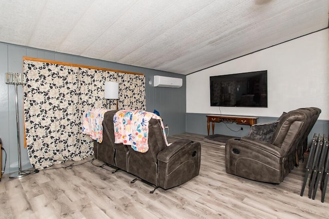 living area featuring lofted ceiling, wood finished floors, and a wall mounted AC