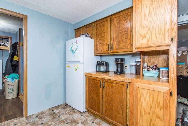 kitchen with brown cabinets, freestanding refrigerator, and light countertops