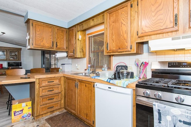 kitchen with under cabinet range hood, a sink, backsplash, dishwasher, and stainless steel range with gas stovetop