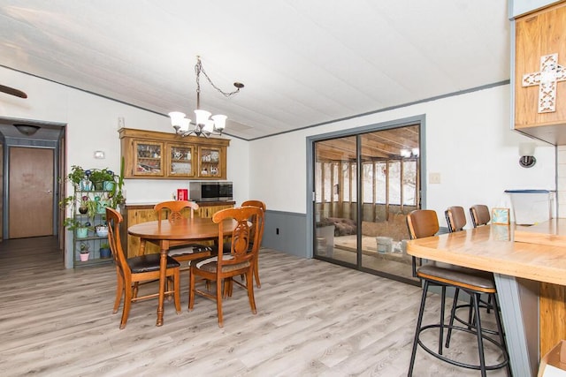 dining area with lofted ceiling, light wood-type flooring, and an inviting chandelier