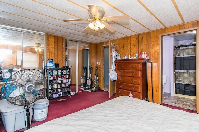 bedroom with ceiling fan, carpet floors, two closets, and wooden walls