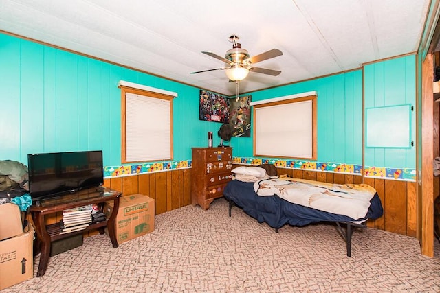 bedroom featuring ceiling fan, carpet floors, and wooden walls