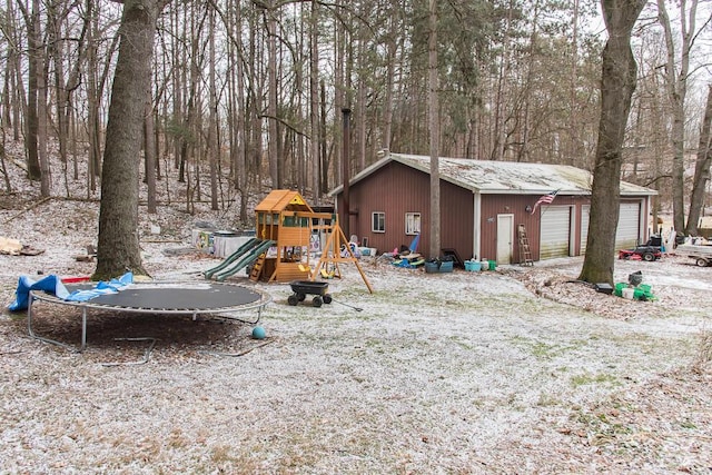 view of yard featuring a trampoline, an outbuilding, a playground, and a detached garage