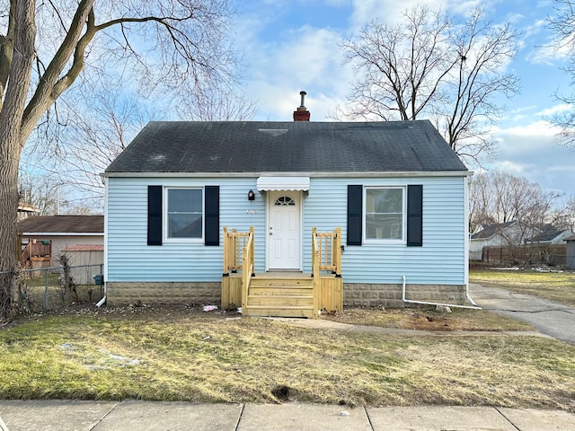 view of front of house with roof with shingles, a chimney, and fence