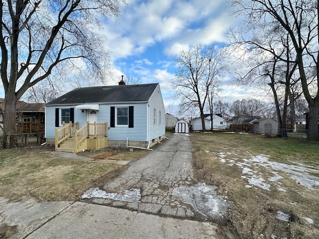 view of front of home featuring a front lawn, fence, an outdoor structure, and aphalt driveway