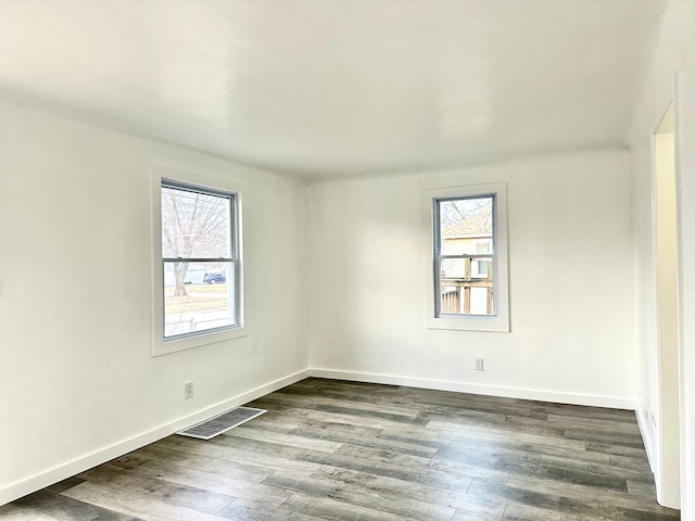 spare room featuring wood finished floors, visible vents, and baseboards