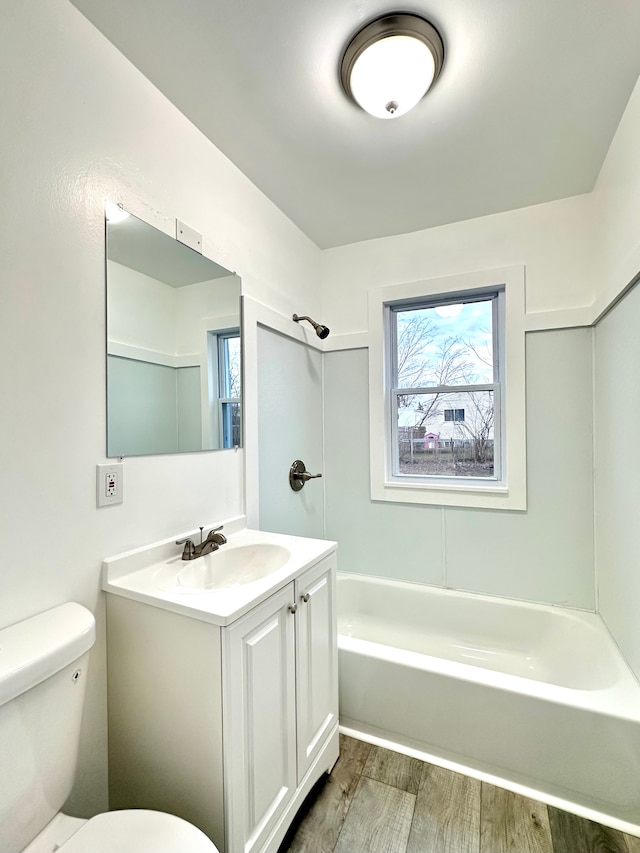 bathroom featuring toilet, shower / bath combination, wood finished floors, and vanity