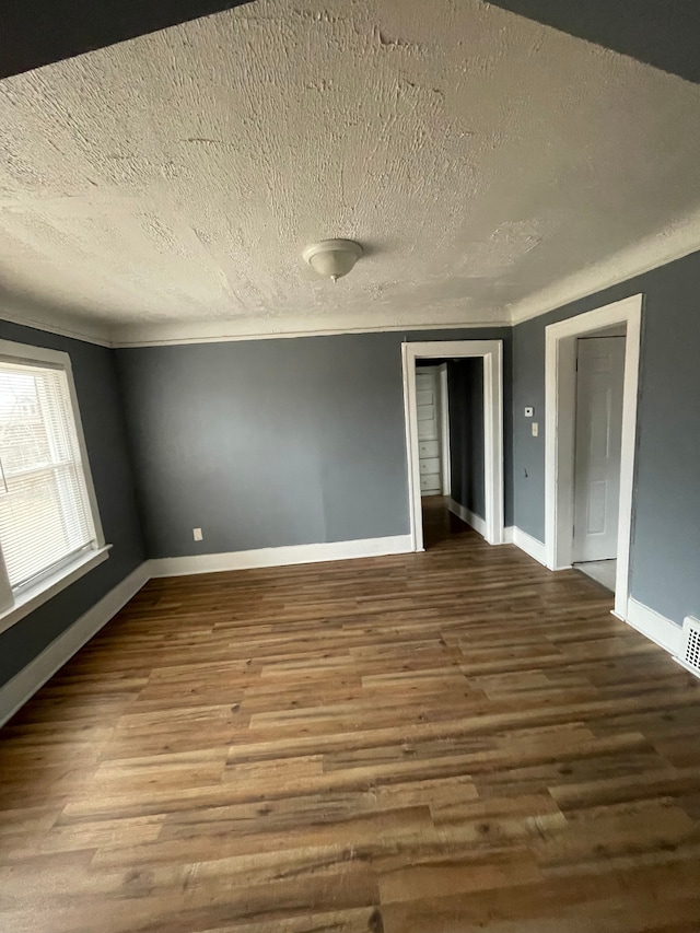 spare room with baseboards, a textured ceiling, visible vents, and wood finished floors