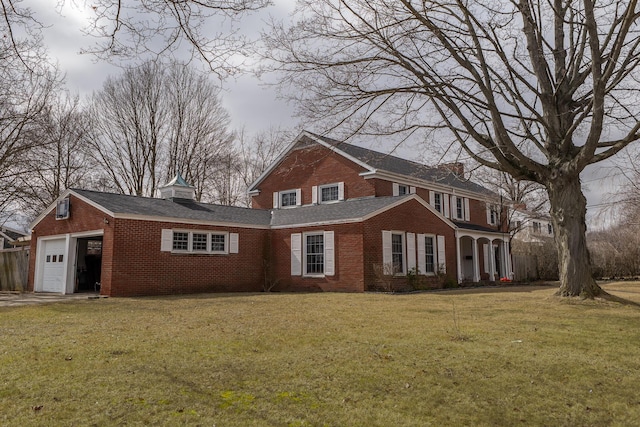 view of front of home featuring a front lawn, brick siding, a chimney, and an attached garage