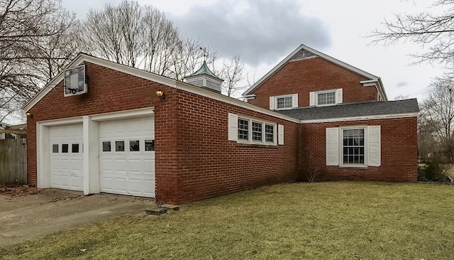 view of side of home with a garage, brick siding, a lawn, and driveway