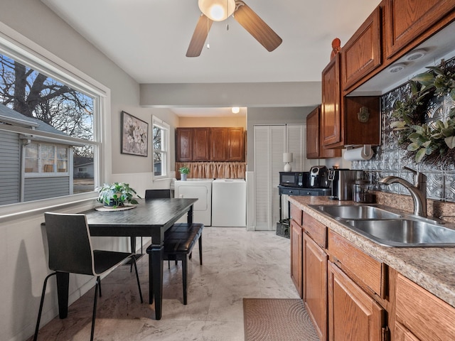 kitchen featuring ceiling fan, light countertops, separate washer and dryer, marble finish floor, and a sink