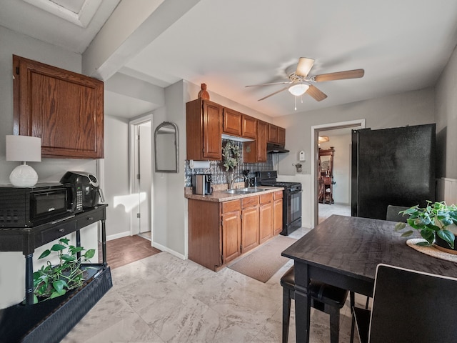 kitchen with ceiling fan, under cabinet range hood, light countertops, black appliances, and a sink